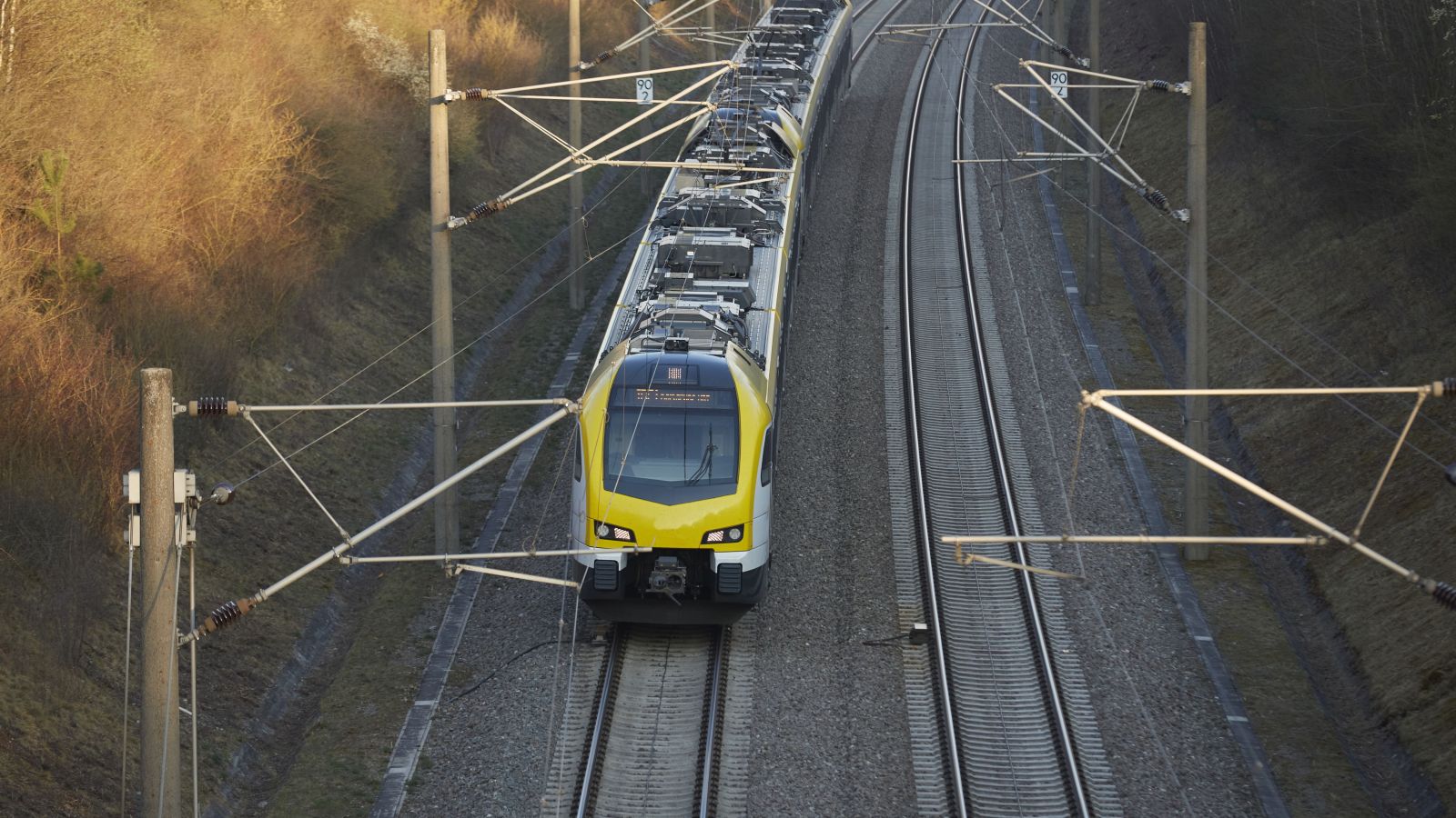 Hochgeschwindigkeitszug auf Gleisen Ein Hochgeschwindigkeitszug fährt auf Gleisen. daneben stehen die Fahrleitungsmasten.